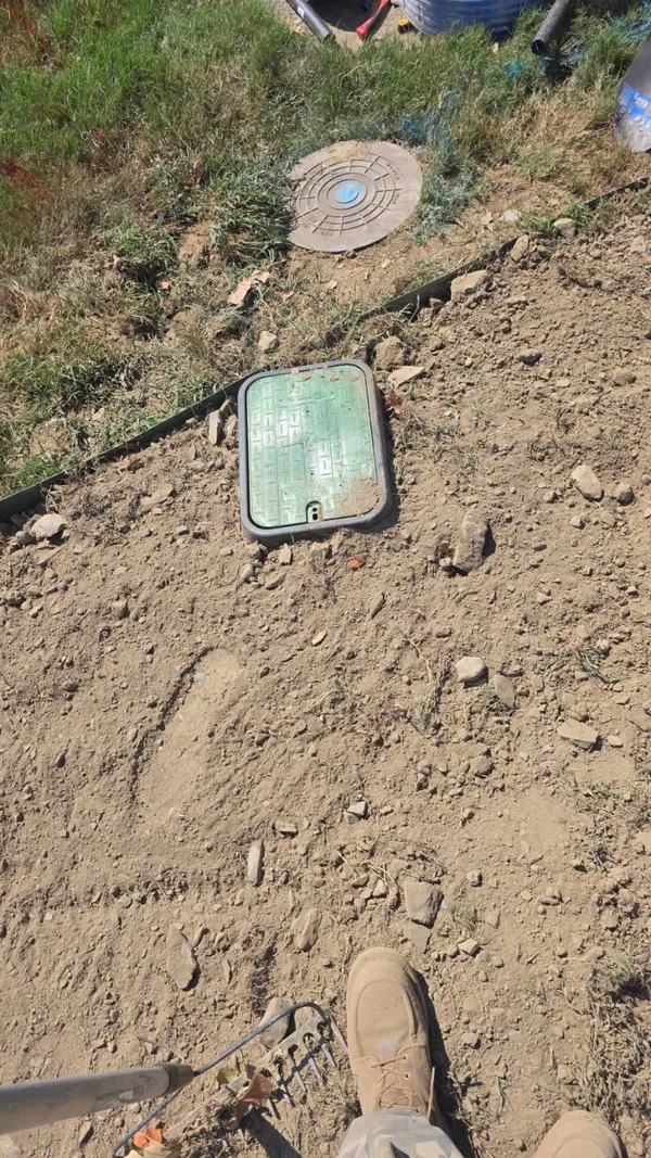 Water meter and valve access boxes set in a freshly backfilled yard after a water line replacement