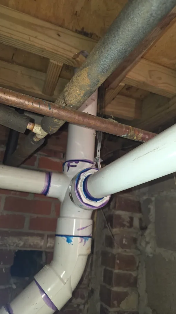 New PVC drain and vent fittings installed in a crawl space under a home