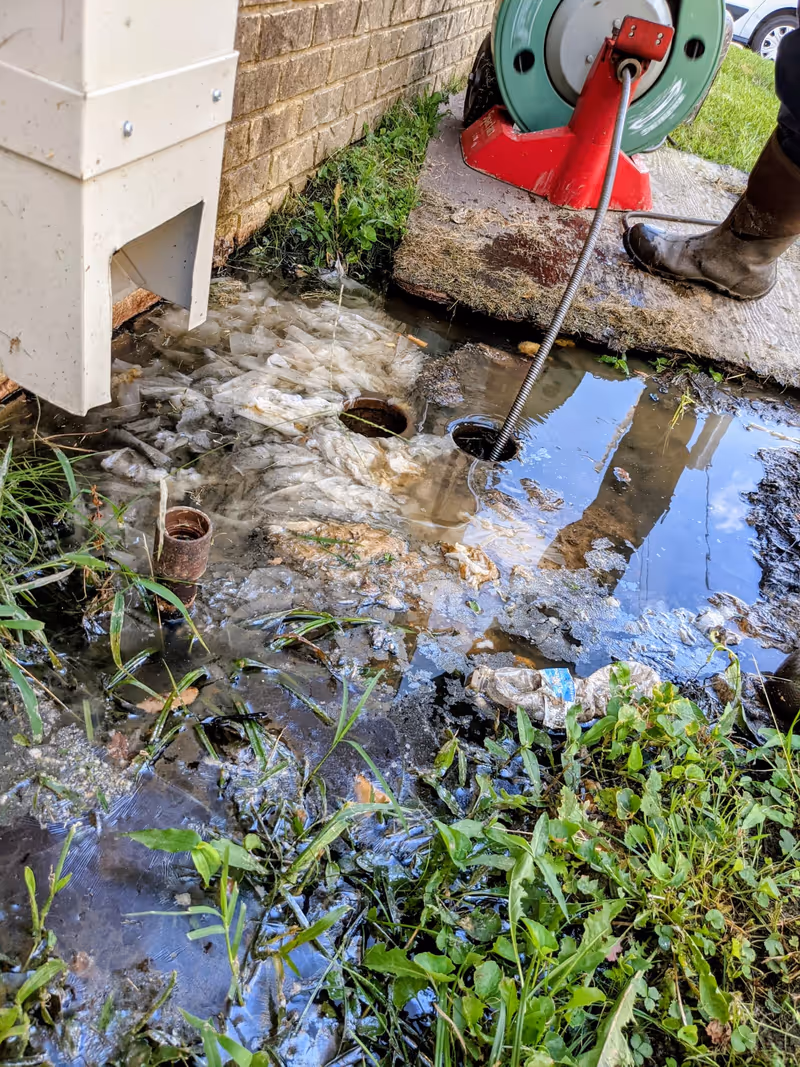 Drain cleaning with a sewer snake outside a building near UALR - sewage backup cleared at the clean-out