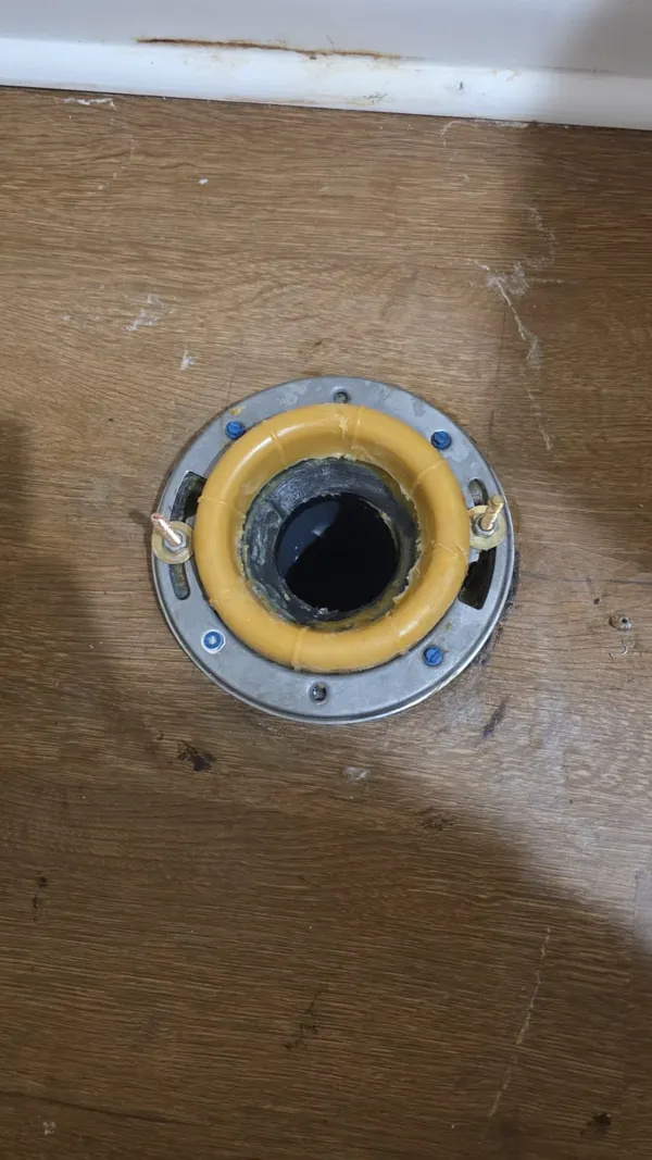 New toilet flange with wax ring set in the floor, ready for toilet installation