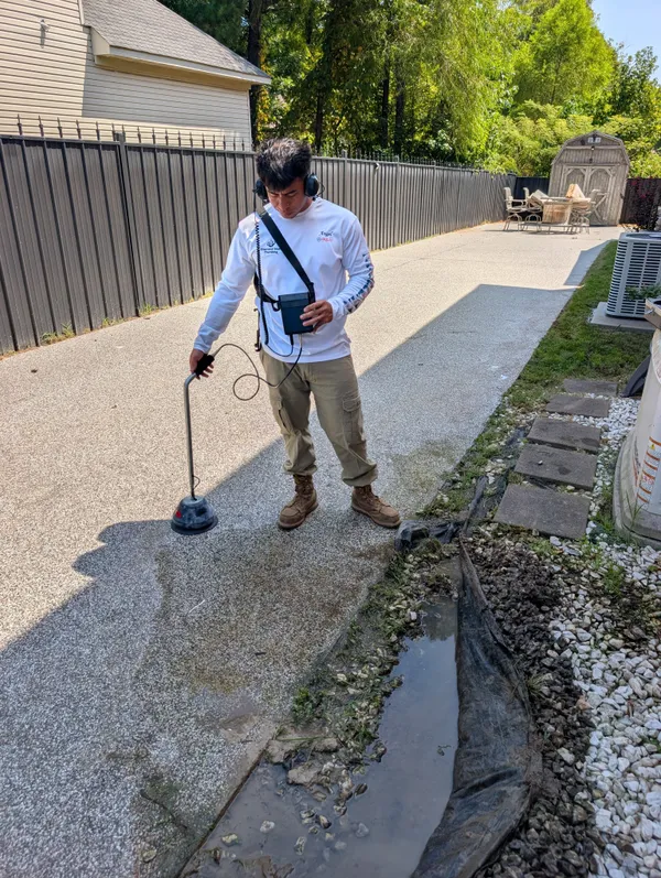 Technician listening for an underground water leak with an acoustic ground microphone