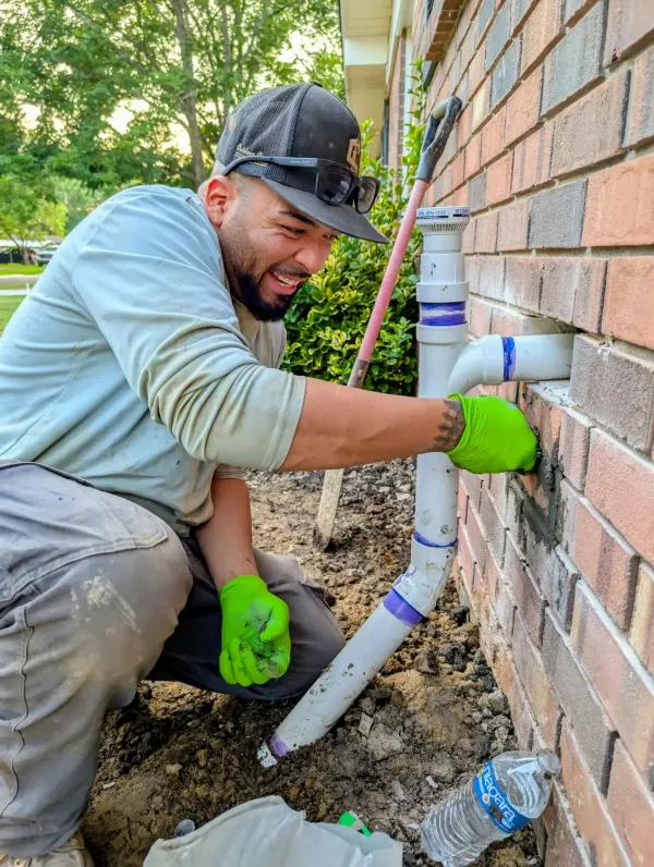 Plumber installing a drain cleanout and vent on an exterior wall