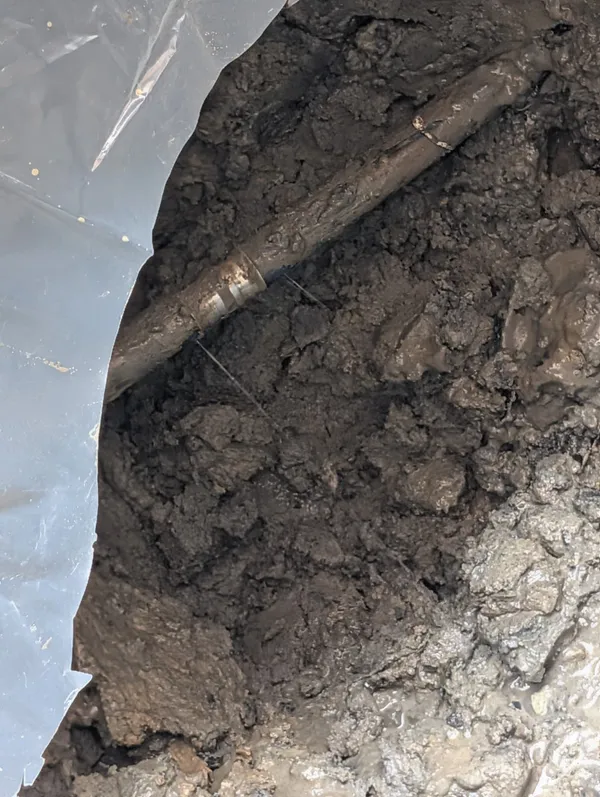 Excavated water pipe exposed in a muddy trench during a pipe repair