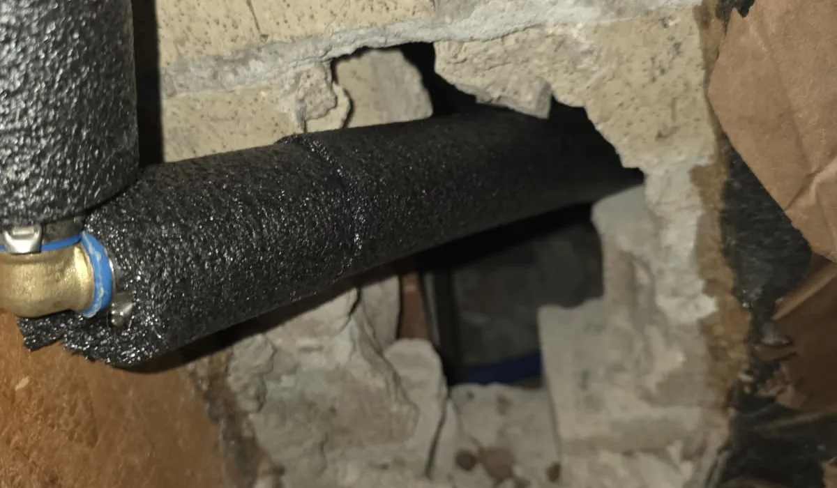 Insulated water lines run beneath floor joists in a crawl space