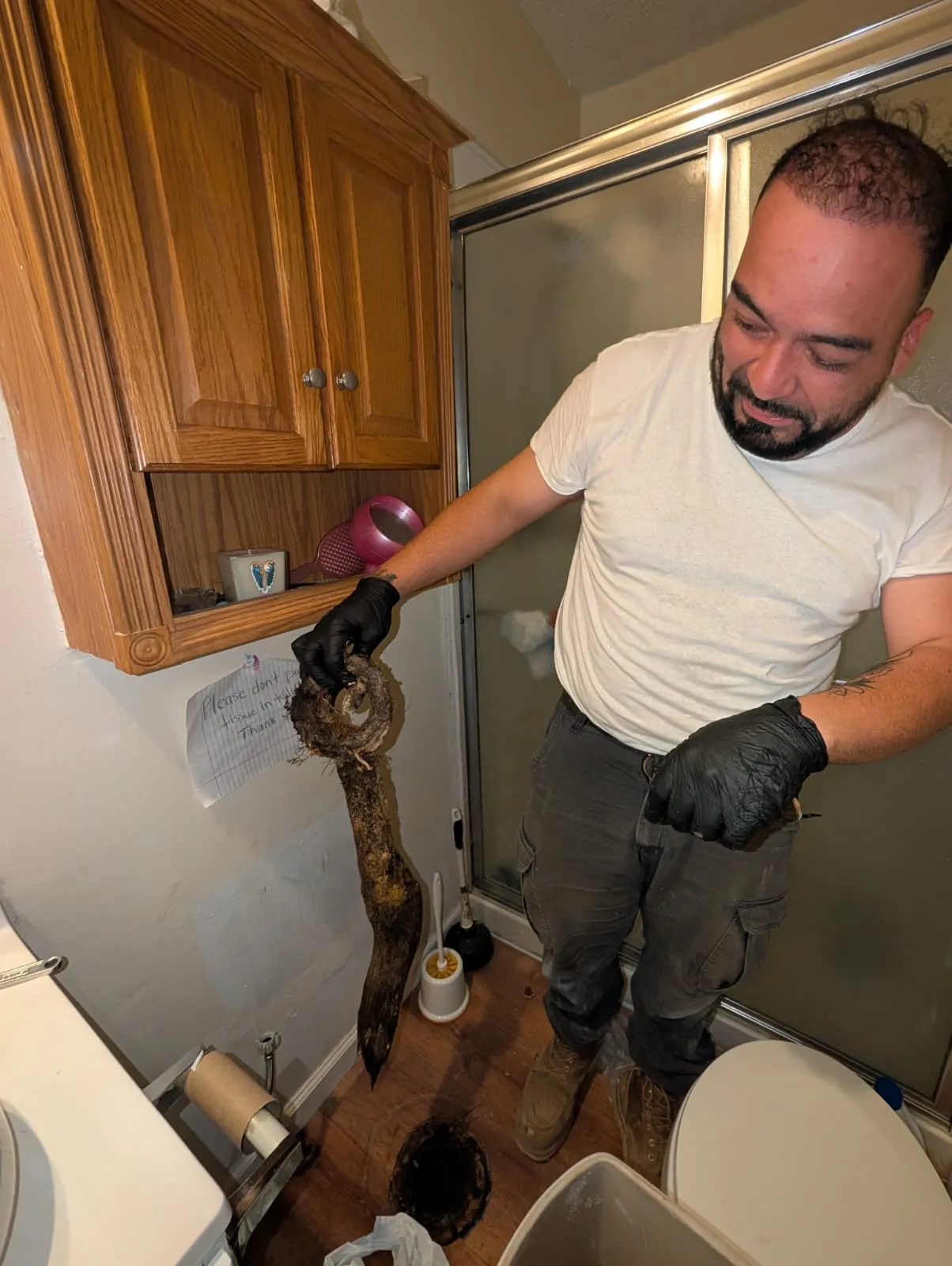 Diamond State Plumbing technician holding tree roots pulled from a clogged bathroom drain