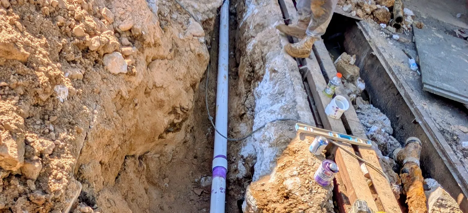 Excavated trench with old and new water service lines